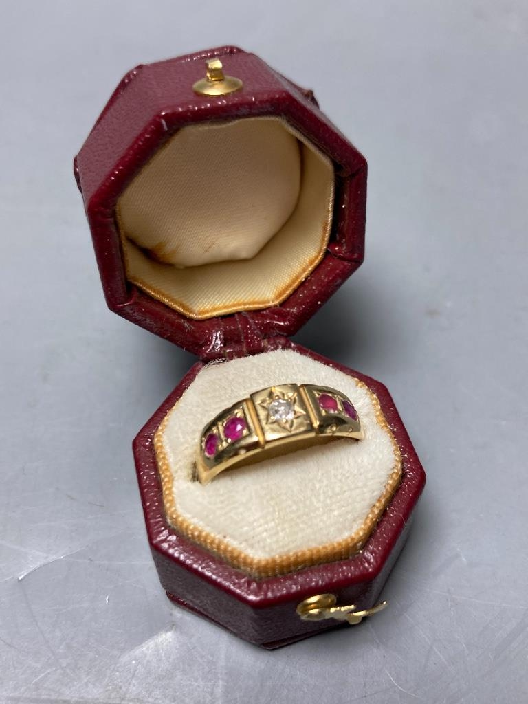 An early 20th century yellow metal, four stone ruby and single stone diamond set half hoop ring